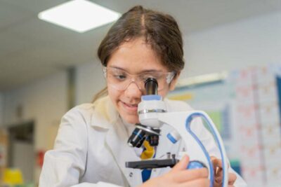 Young student using a microscope in science lessons at school