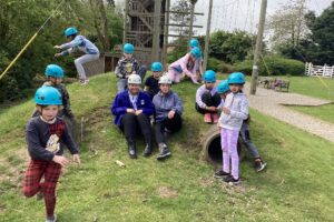 Group of children wearing safety helmets during an outdoor activity on a climbing course