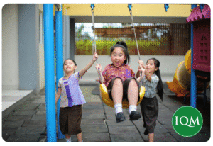 3 primary school students playing together on a swing set