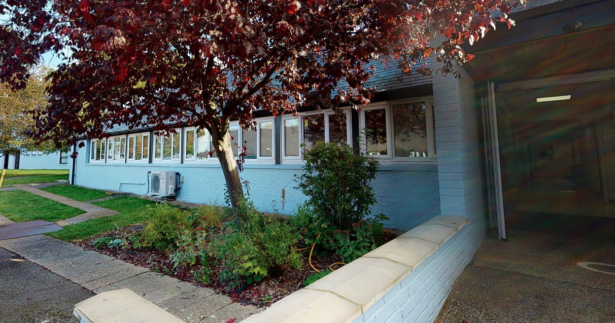 Image of the outside of an entrance to Aurora Meldreth Manor with a tree.
