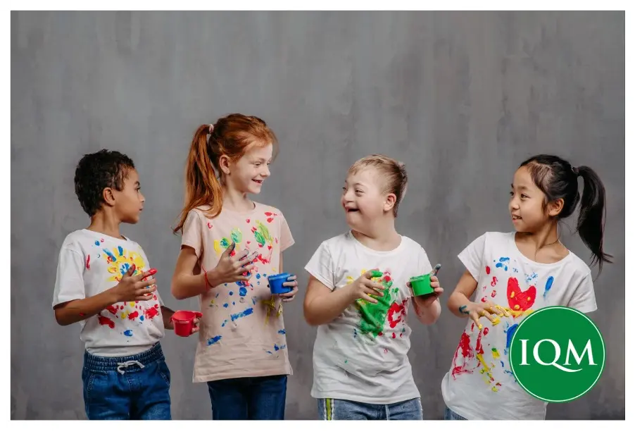 Four children playing with paint in white t-shirts getting very messy clothes and hands