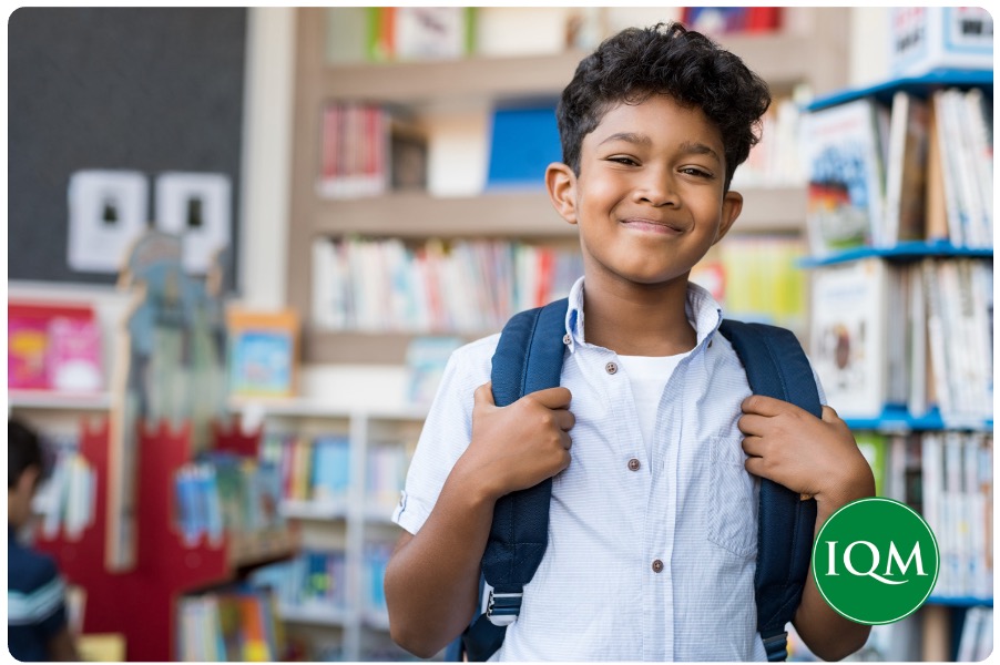 A primary school aged pupil in the library of an international school in Dubai, smiling for the picture.
