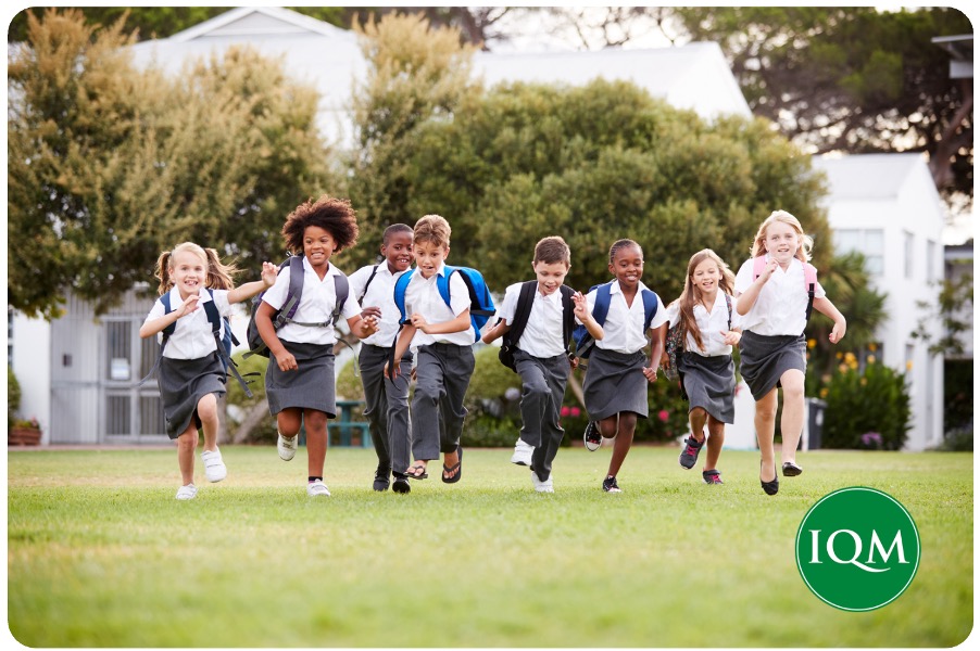 Several primary school pupils running across the lawns of an international school in Dubai.
