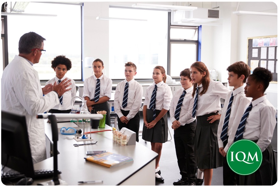 A group of secondary school pupils listening to a science teacher in a hands-on lesson