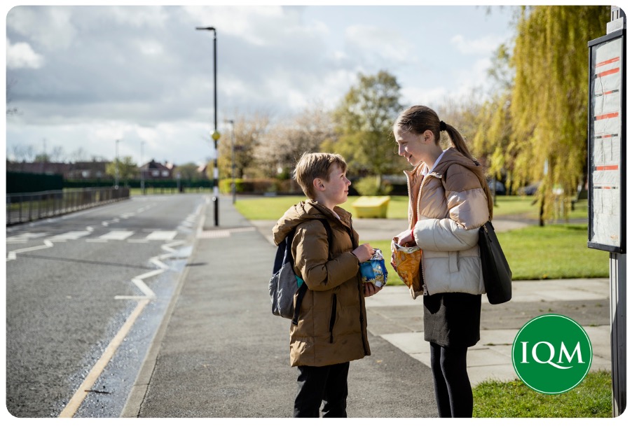 Two secondary school pupils waiting for their school bus to school