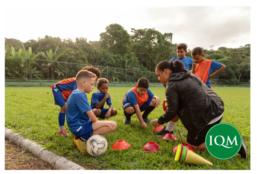 teacher and pupils outside having a PE lesson learning about football