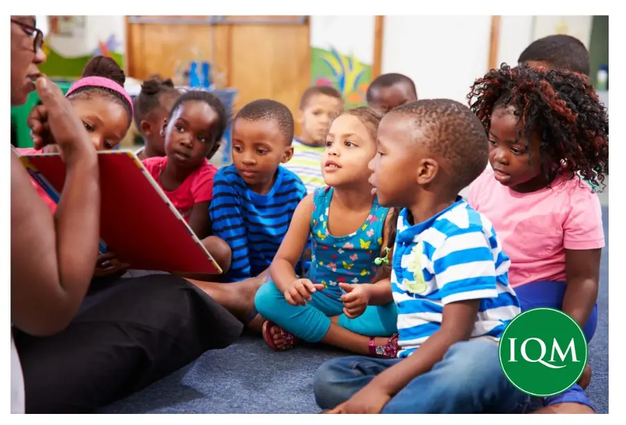 teacher reading a book to class full of children